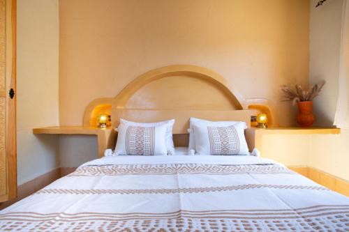 a bedroom with a large white bed with two pillows at Anza surfhouse in Agadir