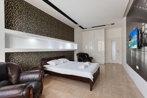 a bedroom with a bed and two leather chairs at Odesa Pearl Apartments in Odesa