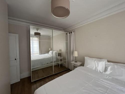 une chambre avec un grand lit blanc et un miroir dans l'établissement Appartement Arc de Triomphe 65 m2, à Paris