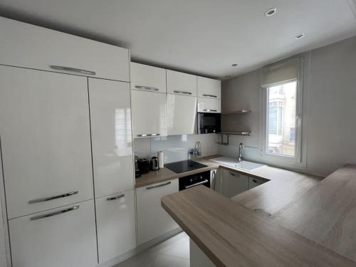 une cuisine avec des armoires blanches et une table en bois dans l'établissement Appartement Arc de Triomphe 65 m2, à Paris