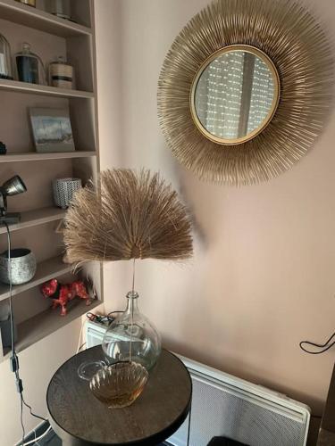 - une table ronde avec un miroir et un vase dans l'établissement Maison moderne proche Golf et plage du Touquet, à Cucq