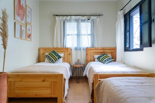 two twin beds in a room with a window at Anza surfhouse in Agadir