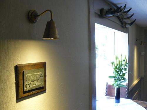 a lamp hanging on a wall with a picture of a plant at The Black Bull Inn in Balsham