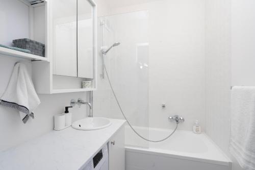 a white bathroom with a shower and a sink at 19 Apart in Gdynia