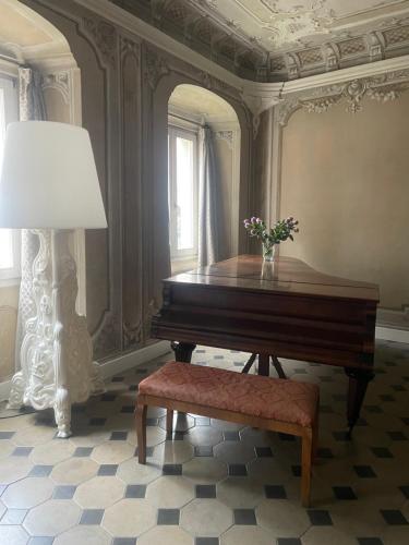 a piano in a room with a lamp and flowers at La Cles Deluxe Suites in Cles