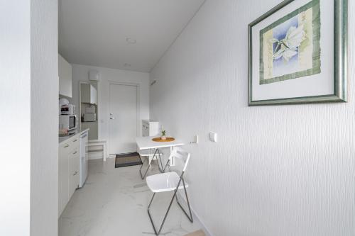 a white kitchen with a table and a picture on the wall at Pramonės Apartment #5 by PoloApartments in Kaunas