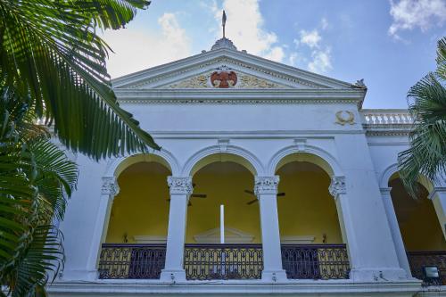 a white building with columns and a flag on top at Royal Orchid Metropole Mysore in Mysore