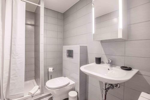 a white bathroom with a toilet and a sink at Saint Laurent 33-35 by Homenhancement in Lausanne