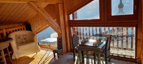 Cette chambre mansardée comprend une chaise, un bureau et des fenêtres. dans l'établissement Appartement spacieux aux Chapelles avec vue sur montagne, à Les Chapelles