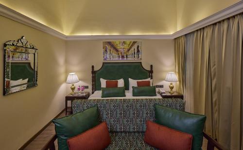 a hotel room with a bed and two chairs at Royal Orchid Metropole Mysore in Mysore