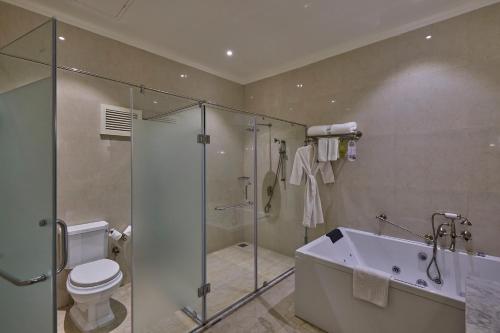 a bathroom with a shower and a tub and a toilet at Royal Orchid Metropole Mysore in Mysore