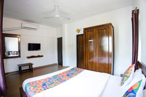 a bedroom with a bed and a wooden door at FabHotel Comfort Stays - Nr Miramar Beach in Panaji