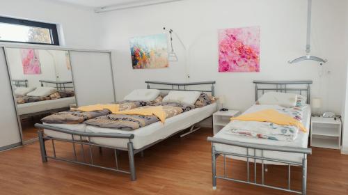 two beds in a room with paintings on the wall at ARES Centrum Kováčová in Kováčová