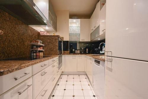 Il comprend une cuisine avec des placards blancs et du carrelage. dans l'établissement Spacious apartment in central Paris, à Paris