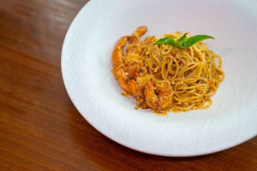 a white plate with pasta on a wooden table at Radisson Hotel Brunei Darussalam in Bandar Seri Begawan