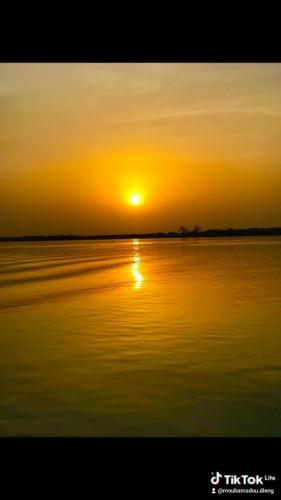 a sunset over a body of water with the sun setting at Auberge Cœur Océan in Joal-Fadiout