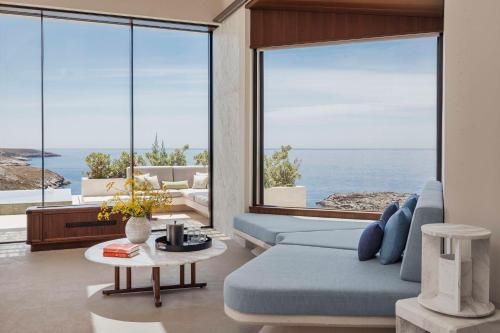 a living room with a blue couch and large windows at One&Only Kéa Island in Pisses