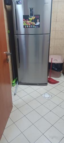 a kitchen with a stainless steel refrigerator on a tiled floor at Super stylish in Ajman 
