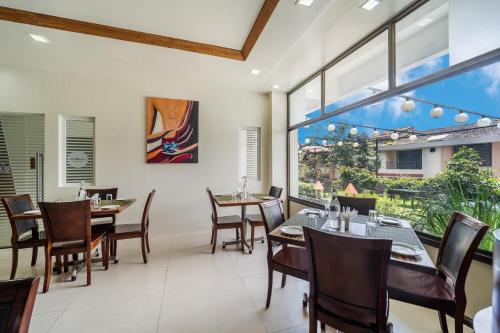 a dining room with tables and chairs and large windows at Sterling Panchgani in Panchgani