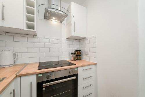 a kitchen with white cabinets and a stove top oven at 4 Beds - City Gateway Getaway with Free Parking in Glasgow