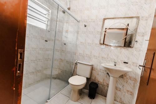 a bathroom with a toilet and a sink and a shower at Tayá Hospedagens in Ubatuba