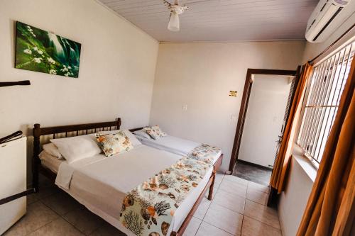 a small bedroom with a bed and a window at Tayá Hospedagens in Ubatuba
