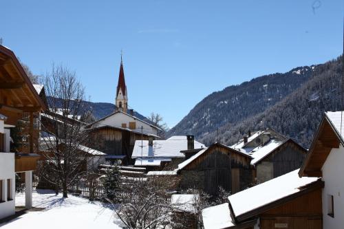 a village covered in snow with a church in the background at Apart Diamant in Nauders