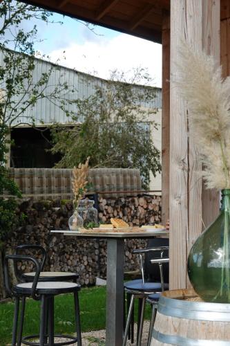 a patio with a table and chairs and a stone wall at Gîte de l’Ambiance in Francheville