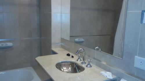 a bathroom with a sink and a mirror and a tub at Hotel Torrevado in Las Grutas