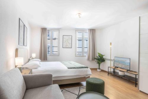 a white bedroom with a bed and a couch at Saint Laurent 33-35 by Homenhancement in Lausanne