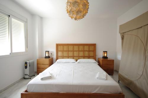 a bedroom with a large bed and a chandelier at Apartamento Livingtarifa Canela in Tarifa