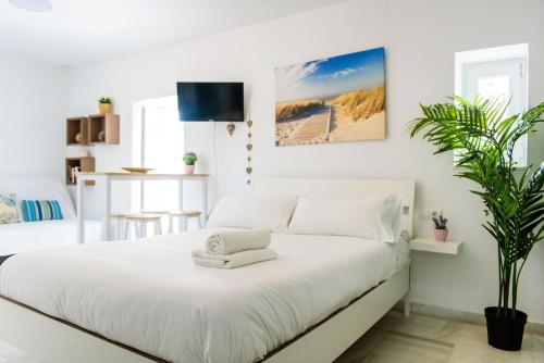 タリファにあるLivingtarifa Apartamento Biancoのタオルが敷かれた白いベッドのある寝室