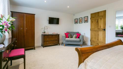a bedroom with a bed and a chair and a television at Cleifiog Fawr in Valley