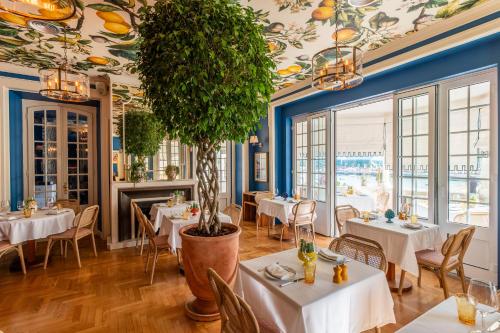 a restaurant with white tables and a potted tree at Villa Cascais Boutique Hotel in Cascais