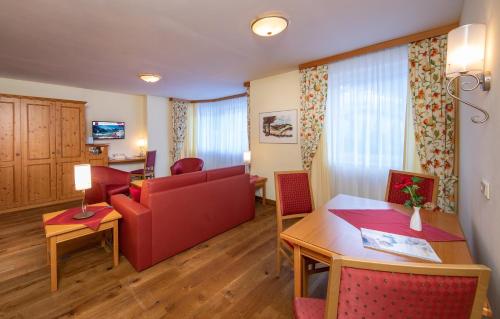 a living room with a red couch and a table at VÖTTER'S HOTEL in Kaprun - summer card included in Kaprun