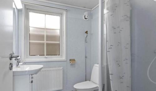 Un baño con inodoro, lavabo y ventana. en Rum mitt stan, en Grebbestad