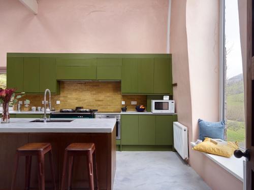 a kitchen with green cabinets and a sink at The Castle, Capel-y-Ffin, The Black Mountains in Abergavenny
