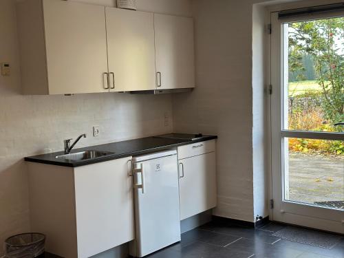 a kitchen with white cabinets and a sink and a window at Tollundgaard Golf Park & Apartments in Funder Kirkeby