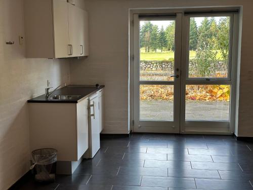 a kitchen with a sink and a sliding glass door at Tollundgaard Golf Park & Apartments in Funder Kirkeby