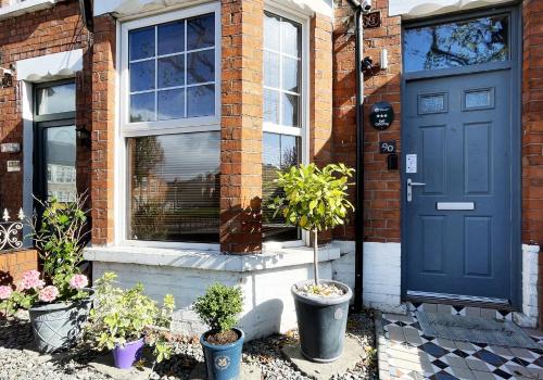 a blue door of a brick house with potted plants at Titanic The Lady -free parking in Belfast