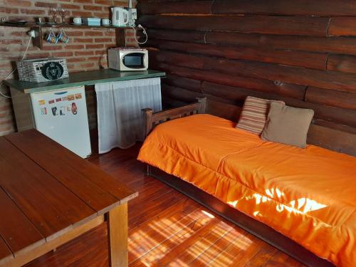 ビジャ・ヘネラル・ベルグラーノにあるAldea Las Calandriasのベッドルーム(オレンジ色のベッド1台、冷蔵庫付)