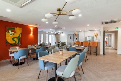 une salle à manger avec des tables et des chaises bleues dans l'établissement Résidence Senior Marina Bay, à Villeneuve-Loubet