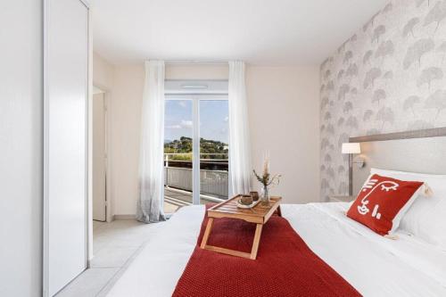 - une chambre avec un lit doté d'une couverture rouge et d'une table dans l'établissement Résidence Senior Marina Bay, à Villeneuve-Loubet