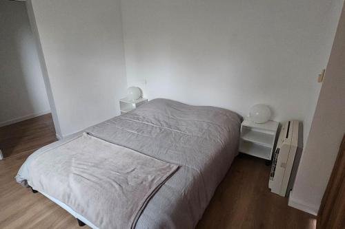 une chambre blanche avec un lit et un parquet dans l'établissement La Maisonnette Des Arcs, aux Arcs-sur-Argens