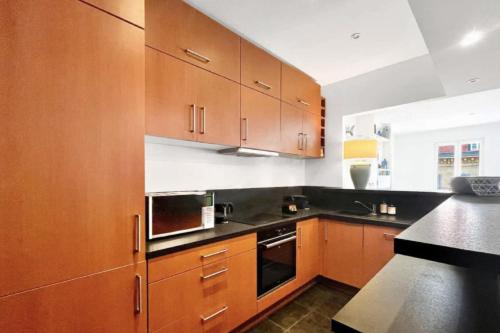 une cuisine avec des armoires en bois et un comptoir noir dans l'établissement NEW 2BR in CANNES CENTER, à Cannes