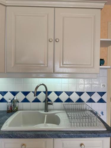 un évier de cuisine avec des armoires blanches et des carreaux bleus et blancs dans l'établissement Studio Ti’Sable 50m de la plage, à Fort-Mahon-Plage
