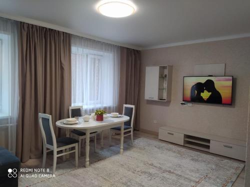 a living room with a table and chairs and a television at VIP Евро-Апартаменты ЖК Женис 2 in Kokshetau