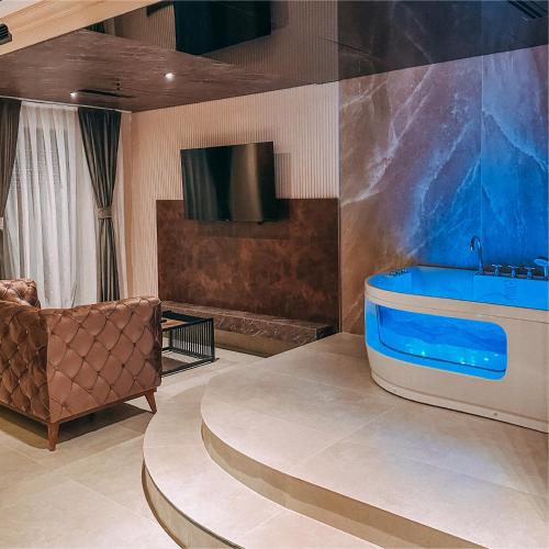 a bathroom with a tub and a couch and a tv at Motel Villa Princi in Kosovo Polje