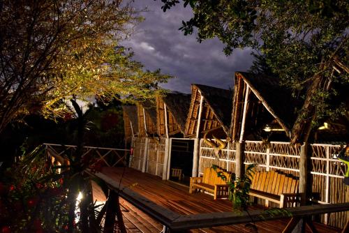 a house with a wooden deck at night at Mara Chui Eco-Resort in Sekenani