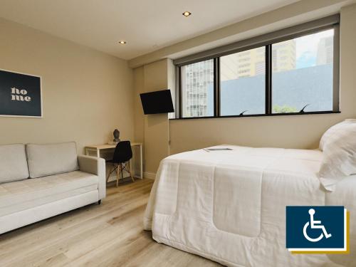 a bedroom with a bed and a couch and a window at Apê Metrô Paulista in Sao Paulo